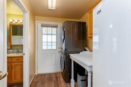 30350 Deer Meadows Rd E, Deer Meadows, WA 99122 - laundry area featuring estacked washer and dryer, cabinet space, and dark wood-style flooring