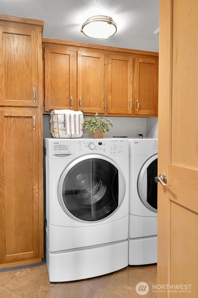 1605 5th Ave N Unit 402, Seattle, WA 98109 - laundry room with cabinet space, washer and dryer, a textured ceiling, and light tile patterned floors