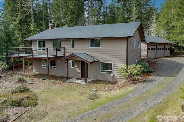 491 N Suncrest Dr, Hoodsport, WA 98548 - view of front of home with a garage, a chimney, a wooden deck, a view of trees, and roof with shingles