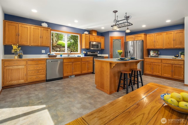 3120 Wave Dr, Everett, WA 98203 - kitchen featuring appliances with stainless steel finishes, a kitchen breakfast bar, brown cabinetry, and recessed lighting