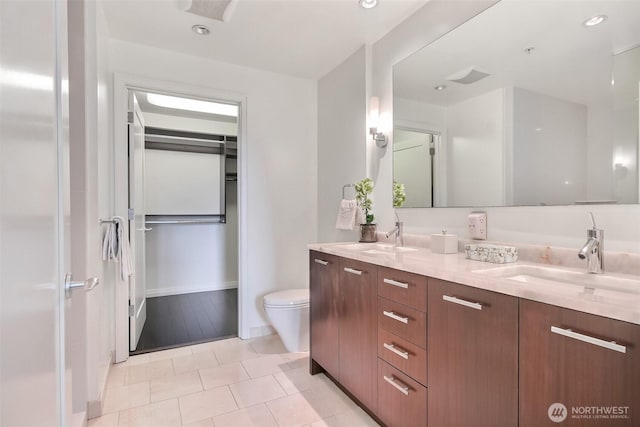 10700 NE 4th St Unit 1006, Bellevue, WA 98004 - bathroom featuring double vanity, toilet, tile patterned floors, a spacious closet, and recessed lighting
