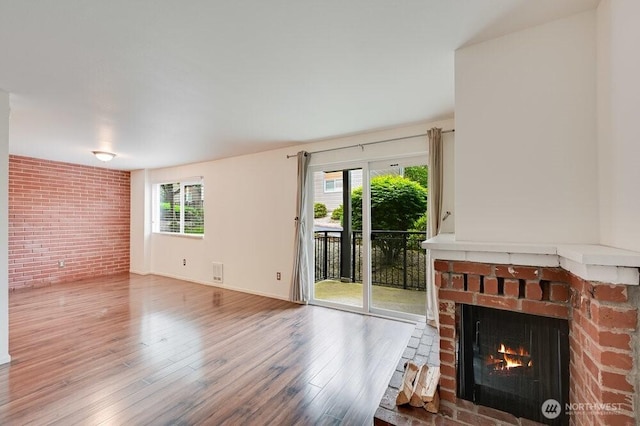 220 SW Clark St Unit B101, Issaquah, WA 98027 - unfurnished living room with a fireplace, plenty of natural light, wood finished floors, and brick wall
