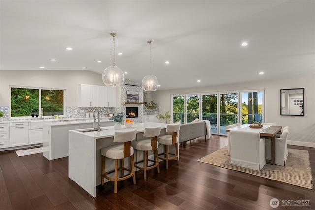 7429 NE 129th St, Kirkland, WA 98034 - kitchen featuring a kitchen island with sink, a sink, a large fireplace, decorative backsplash, and lofted ceiling