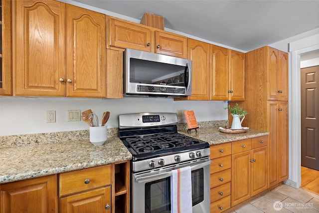 kitchen with stainless steel appliances, light stone counters, and brown cabinetry