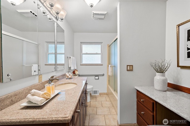 bathroom featuring a shower with door, toilet, vanity, baseboards, and tile patterned flooring