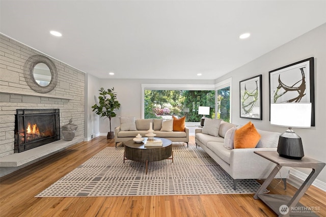 living area with wood finished floors, a fireplace, recessed lighting, and baseboards