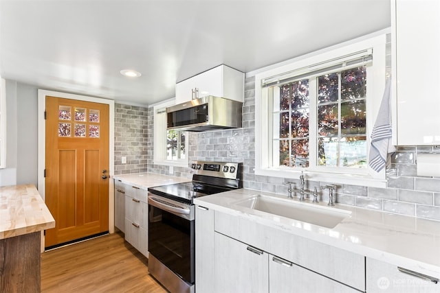 232 N Sunset Dr, Camano Island, WA 98282 - kitchen with appliances with stainless steel finishes, a sink, backsplash, light wood-style flooring, and white cabinetry