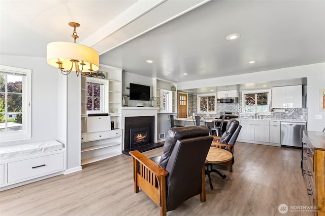 232 N Sunset Dr, Camano Island, WA 98282 - living room with a warm lit fireplace, light wood-style flooring, a chandelier, and recessed lighting