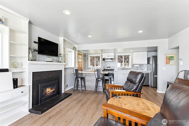 232 N Sunset Dr, Camano Island, WA 98282 - living area with light wood-style floors, a glass covered fireplace, recessed lighting, and baseboards