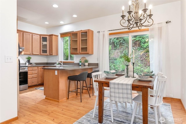 26 Inglewood Pl, Bellingham, WA 98229 - kitchen featuring dark countertops, stainless steel range with electric cooktop, light wood-style floors, a chandelier, and a breakfast bar area