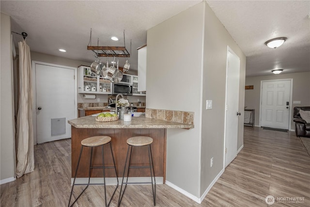 307 E Wilson St, Yacolt, WA 98675 - kitchen with a peninsula, light wood-style flooring, open shelves, stainless steel microwave, and baseboards