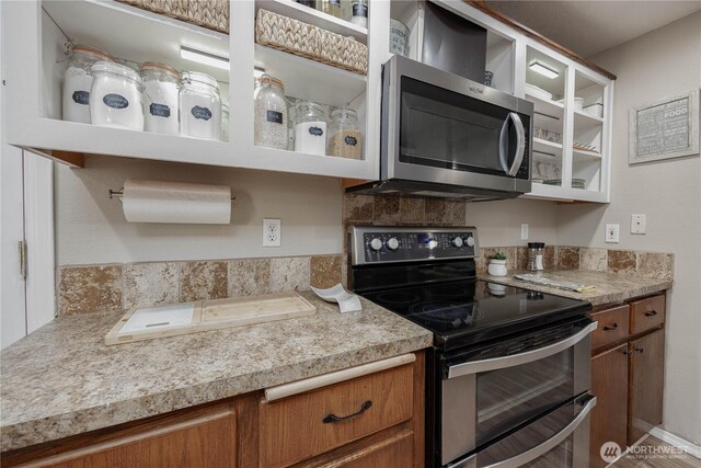 307 E Wilson St, Yacolt, WA 98675 - kitchen featuring appliances with stainless steel finishes, brown cabinets, light countertops, glass insert cabinets, and tasteful backsplash