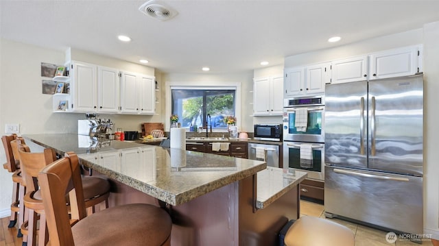 3514 Long Lake Dr SE, Lacey, WA 98503 - kitchen featuring stainless steel appliances, open shelves, a kitchen bar, a peninsula, and white cabinetry