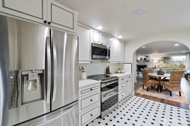 10220 NE Lafayette Ave, Bainbridge Island, WA 98110 - kitchen with stainless steel appliances, arched walkways, light countertops, tasteful backsplash, and white cabinets