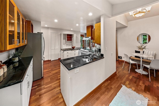 18527 Butternut Rd, Lynnwood, WA 98037 - kitchen featuring dark countertops, dark wood-style flooring, under cabinet range hood, brown cabinets, and recessed lighting