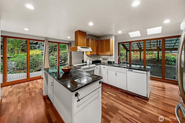 18527 Butternut Rd, Lynnwood, WA 98037 - kitchen featuring white dishwasher, a skylight, stove, dark countertops, and light wood finished floors