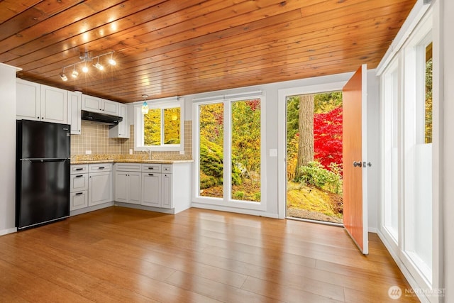 18527 Butternut Rd, Lynnwood, WA 98037 - kitchen featuring freestanding refrigerator, under cabinet range hood, tasteful backsplash, wooden ceiling, and white cabinets