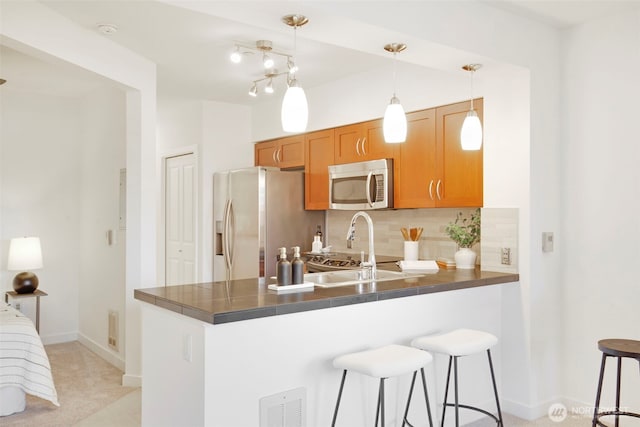 5450 Leary Ave NW Unit 442, Seattle, WA 98107 - kitchen featuring stainless steel appliances, a peninsula, a kitchen breakfast bar, decorative backsplash, and brown cabinets