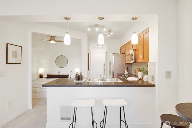 5450 Leary Ave NW Unit 442, Seattle, WA 98107 - kitchen featuring stainless steel microwave, dark countertops, a peninsula, a breakfast bar area, and freestanding refrigerator