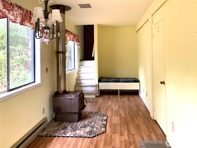 419 Draconis Ave SE, Ocean Shores, WA 98569 - bedroom featuring a baseboard heating unit, a chandelier, multiple windows, and wood finished floors