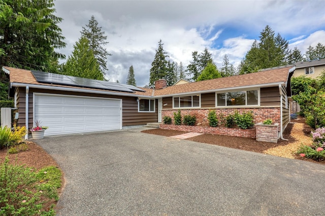 20010 3rd Ave NW, Shoreline, WA 98177 - ranch-style house featuring a garage, driveway, roof mounted solar panels, a chimney, and brick siding