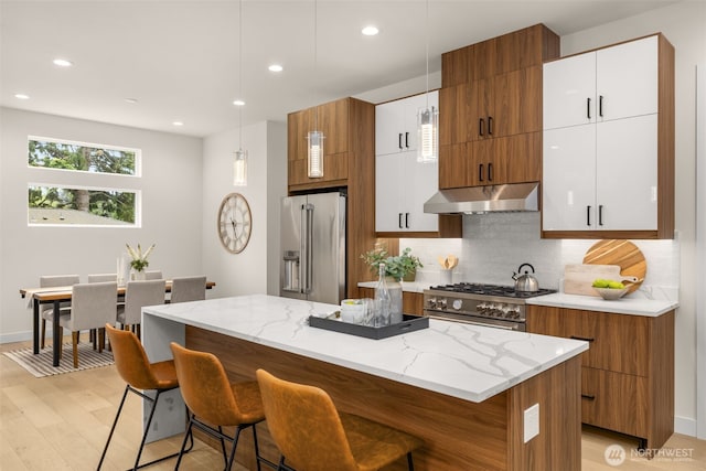 2727 50th Ave SW, Seattle, WA 98116 - kitchen with premium appliances, under cabinet range hood, a breakfast bar, brown cabinets, and recessed lighting