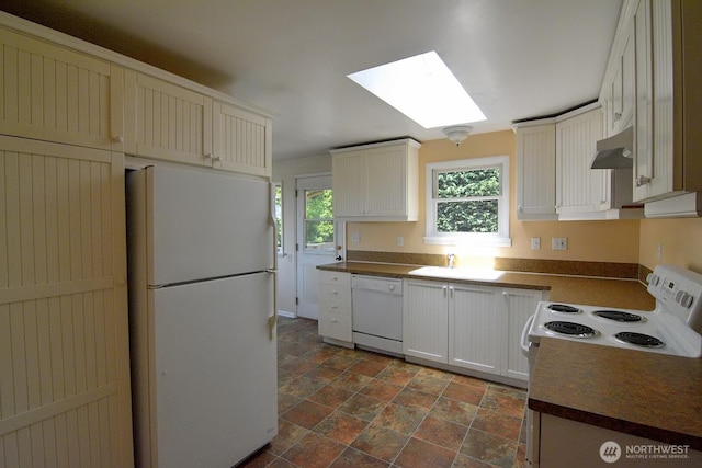 2116 N 86th St, Seattle, WA 98103 - kitchen with white appliances, a skylight, stone finish floors, dark countertops, and under cabinet range hood