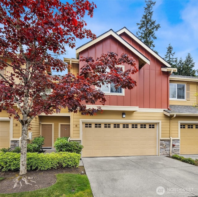 18526 36th Ave W Unit C, Lynnwood, WA 98037 - view of front of house featuring board and batten siding, driveway, an attached garage, and stone siding