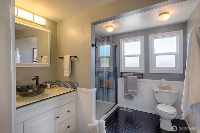 25718 16th Ave S, Des Moines, WA 98198 - bathroom with wainscoting, vanity, a stall shower, toilet, and wood tiled floors