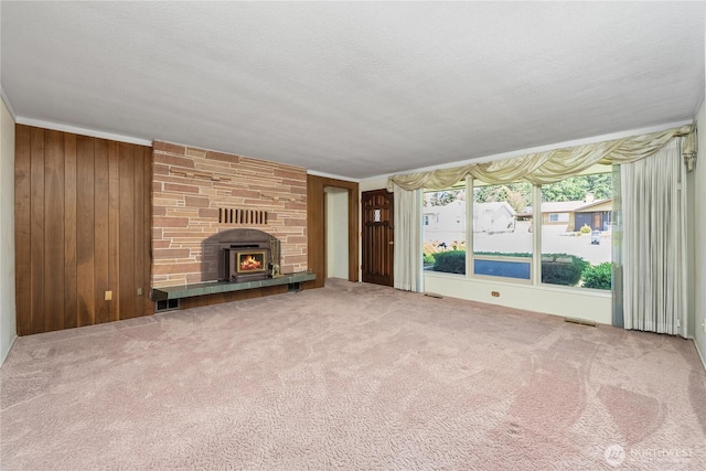 2815 NE Wyoming St, Bremerton, WA 98310 - unfurnished living room with carpet flooring, wood walls, a stone fireplace, and a textured ceiling