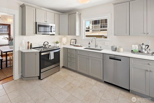 116 E Edgar St, Seattle, WA 98102 - kitchen featuring appliances with stainless steel finishes, gray cabinetry, a sink, light countertops, and light tile patterned flooring