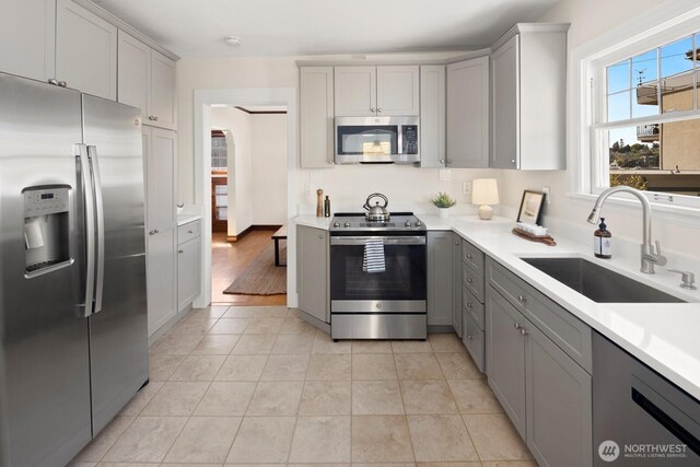 116 E Edgar St, Seattle, WA 98102 - kitchen with appliances with stainless steel finishes, gray cabinetry, a sink, light countertops, and light tile patterned floors
