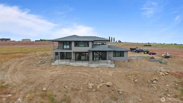 6988 Stonecrest Rd NE, Moses Lake, WA 98837 - view of front facade with a sunroom, a balcony, a view of countryside, and roof with shingles