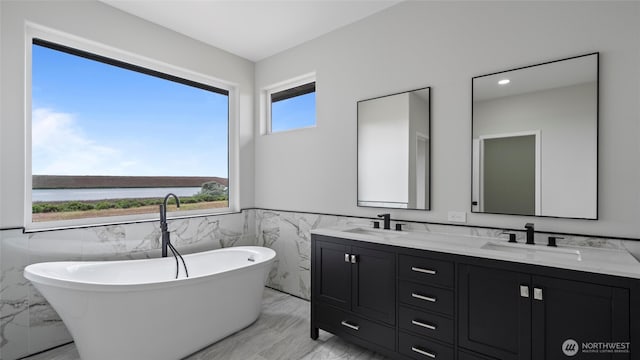 6988 Stonecrest Rd NE, Moses Lake, WA 98837 - bathroom with marble tiled floors, tile walls, a wainscoted wall, double vanity, and a freestanding tub