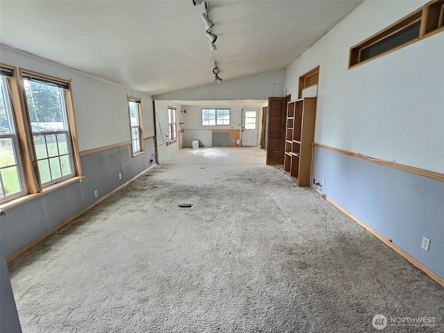 8304 192nd Street Ct E Unit 24, Spanaway, WA 98387 - unfurnished living room featuring track lighting, vaulted ceiling, carpet flooring, and healthy amount of natural light