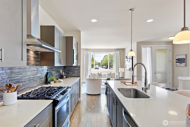 938 SW 97th St, Seattle, WA 98106 - kitchen with stainless steel appliances, wall chimney range hood, a sink, light wood-type flooring, and light countertops