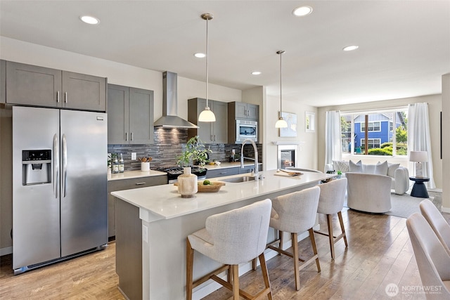 938 SW 97th St, Seattle, WA 98106 - kitchen featuring appliances with stainless steel finishes, wall chimney exhaust hood, a sink, light countertops, and tasteful backsplash