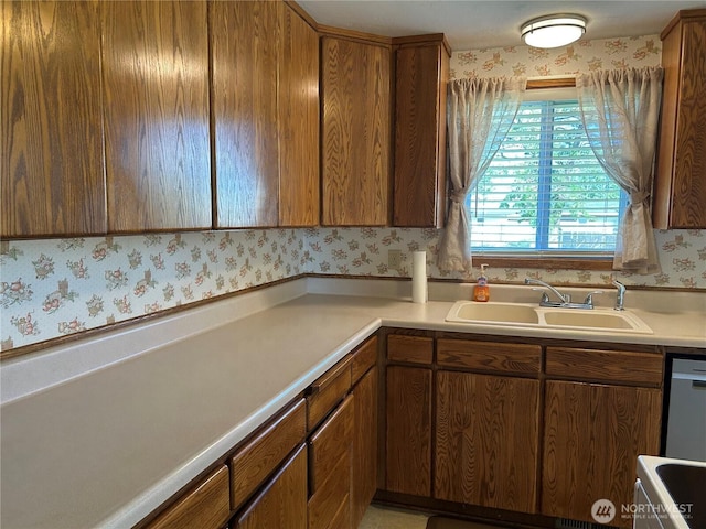 822 S Evergreen Dr, Moses Lake, WA 98837 - kitchen featuring a sink, wallpapered walls, light countertops, dishwasher, and brown cabinetry