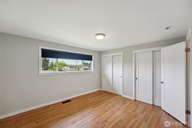 1012 9th Ave N, Edmonds, WA 98020 - unfurnished bedroom featuring two closets, light wood finished floors, and baseboards