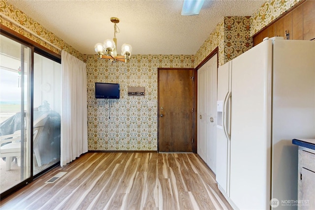 1220 Valley Vista Ave, Walla Walla, WA 99362 - unfurnished dining area with wallpapered walls, a chandelier, light wood-style flooring, and a textured ceiling