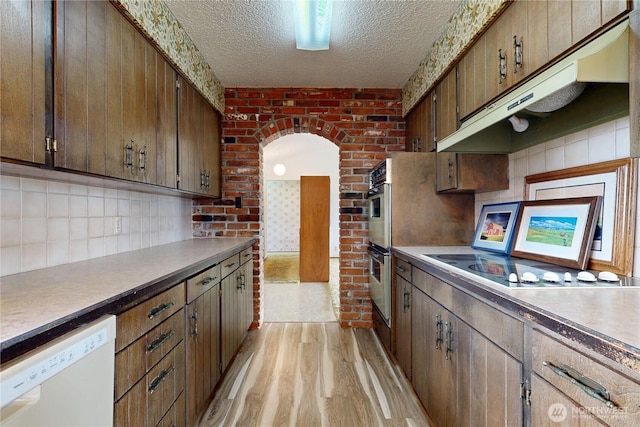 1220 Valley Vista Ave, Walla Walla, WA 99362 - kitchen with white dishwasher, light wood-style flooring, under cabinet range hood, a textured ceiling, and backsplash