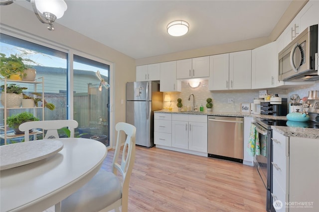 20620 76th Ave W Unit A, Edmonds, WA 98026 - kitchen featuring stainless steel appliances, a sink, white cabinets, light wood-style flooring, and decorative backsplash