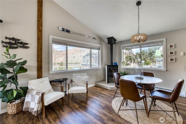421 Lakeview Dr, Orondo, WA 98843 - dining area with a wood stove, wood finished floors, a chandelier, vaulted ceiling, and baseboards