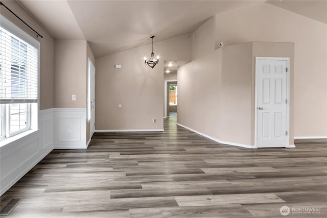15127 148th Avenue Ct E, Orting, WA 98360 - unfurnished dining area featuring lofted ceiling, a chandelier, wood finished floors, and a wainscoted wall