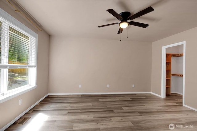 15127 148th Avenue Ct E, Orting, WA 98360 - unfurnished bedroom with wood finished floors, a walk in closet, baseboards, ceiling fan, and a closet