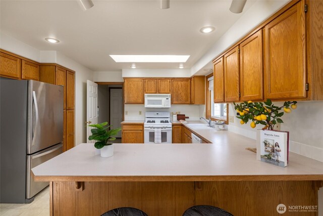 3901 Sterling Pl, Anacortes, WA 98221 - kitchen with white appliances, a sink, light countertops, a peninsula, and a skylight