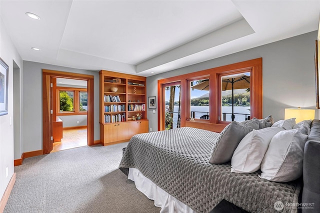 891 E Lake Samish Dr, Bellingham, WA 98229 - carpeted bedroom featuring baseboards, access to exterior, a tray ceiling, recessed lighting, and a water view