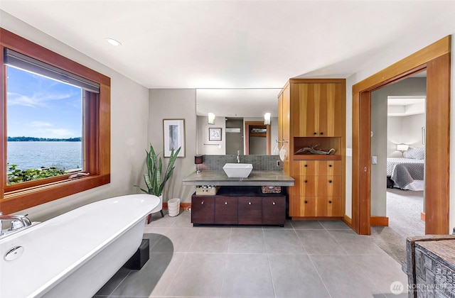 891 E Lake Samish Dr, Bellingham, WA 98229 - ensuite bathroom featuring vanity, a freestanding bath, tile patterned flooring, a water view, and baseboards