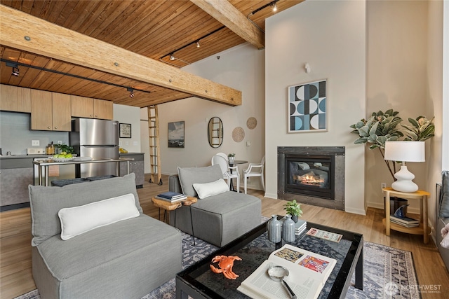 1812 19th Ave Unit 205, Seattle, WA 98122 - living room with rail lighting, wood ceiling with exposed beams, baseboards, a glass covered fireplace, and light wood-style floors