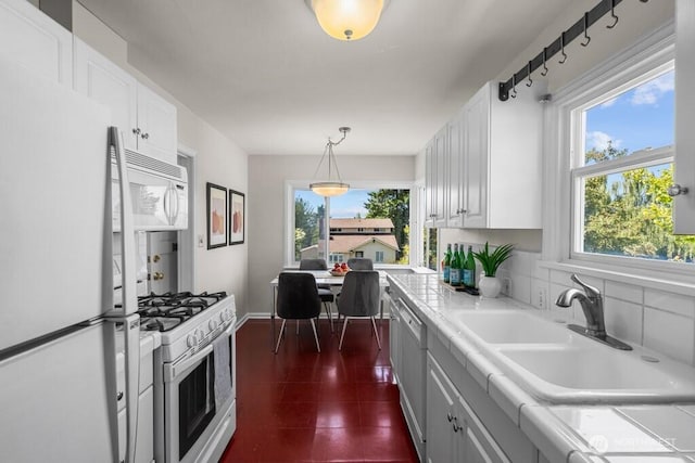 6050 36th Ave SW, Seattle, WA 98126 - kitchen featuring white appliances, a sink, white cabinets, light countertops, and hanging light fixtures